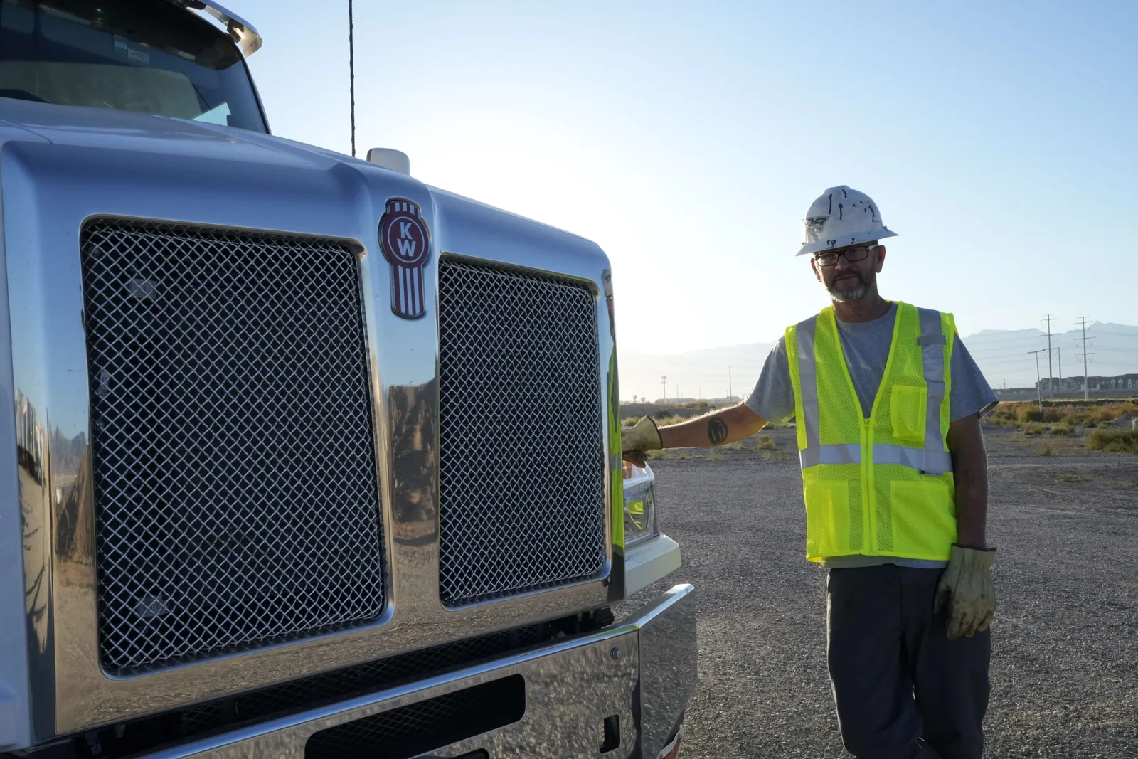 Full Tilt driver wearing safety gear beside a roll-off truck