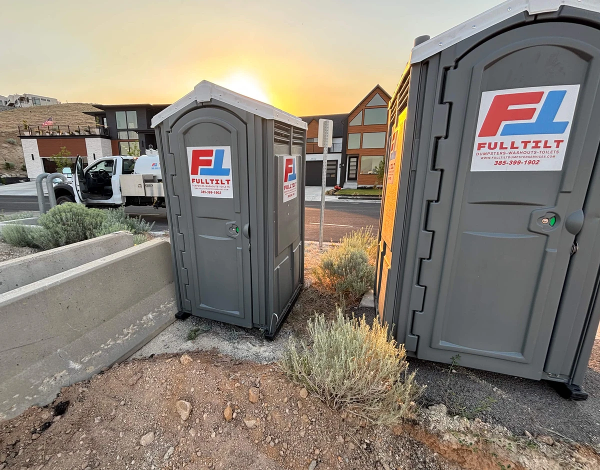 Full Tilt branded portable toilets at an outdoor jobsite